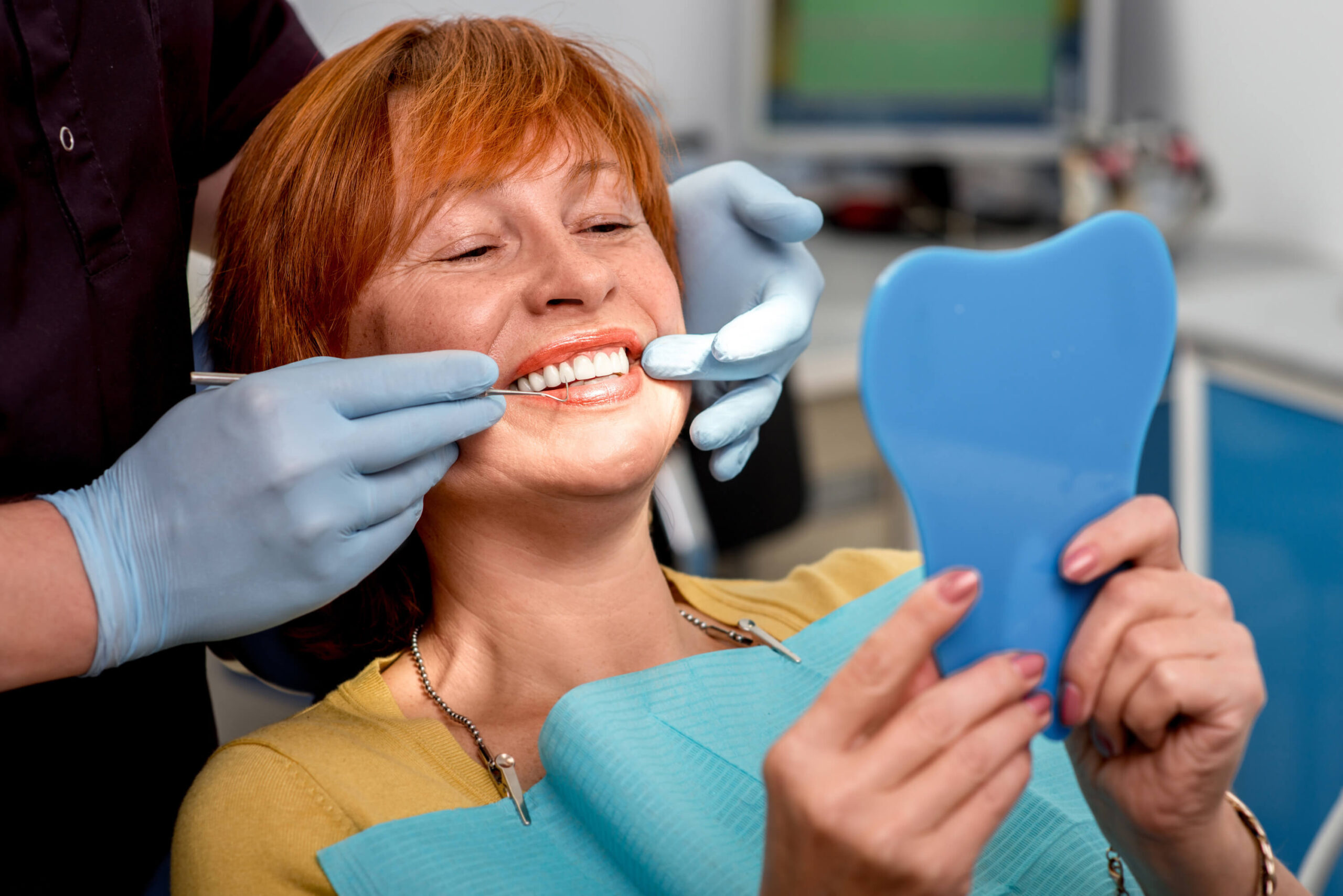 middle aged woman-looking into mirror in dental chair