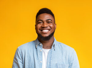 Portrait of young smiling african american guy with beard over yellow background