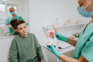 https://www.pexels.com/photo/dentist-holding-a-dental-model-6627330/ Young man at a routine dental exam